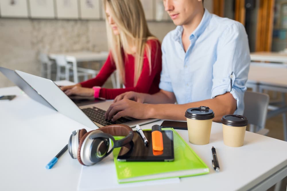 Ein Mann und eine Frau arbeiten nebeneinander an ihren Laptops.
