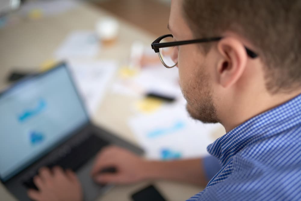 Ein Mann mit Brille arbeitet an seinem Laptop.