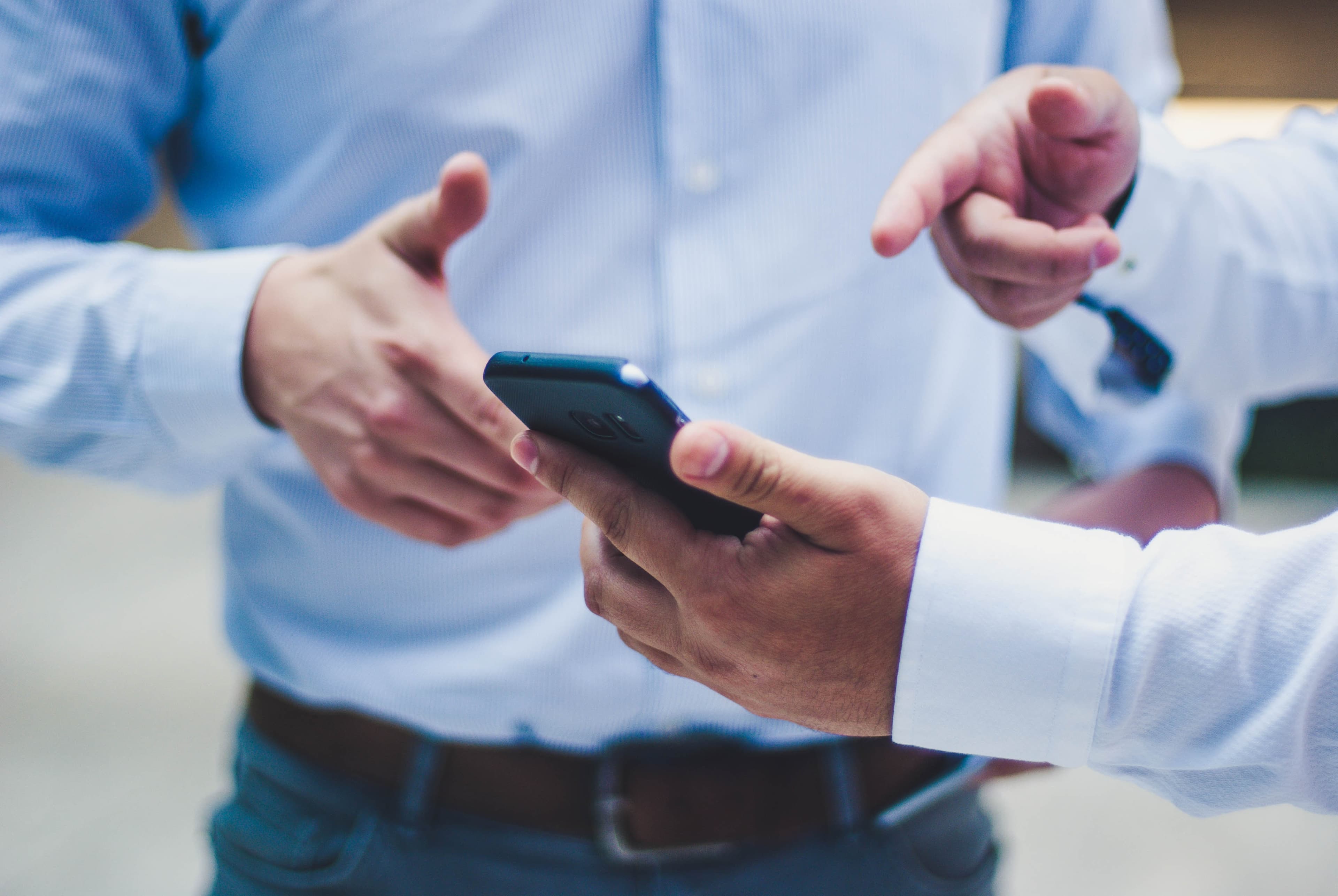 Zwei Personen zeigen auf ein Smartphone.